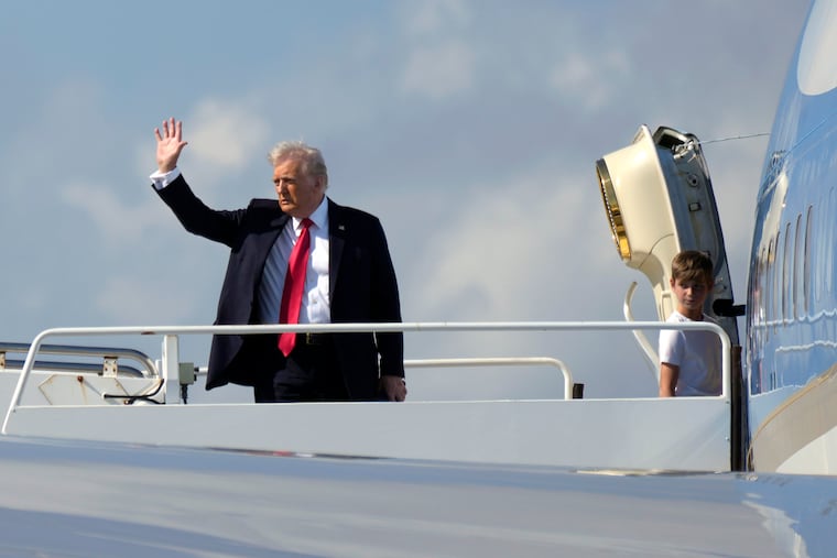 President Donald Trump waves as he boards Air Force One with grandson Theodore, Ivanka Trump's son, at Palm Beach International Airport on Sunday.