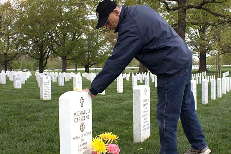 Joseph Crescenz touches his brother's headstone at Arlington National Cemetery. He remembers the day in 1970 he learned his brother, killed two years earlier, would be awarded the Medal of Honor. ROBERT MORAN / Staff