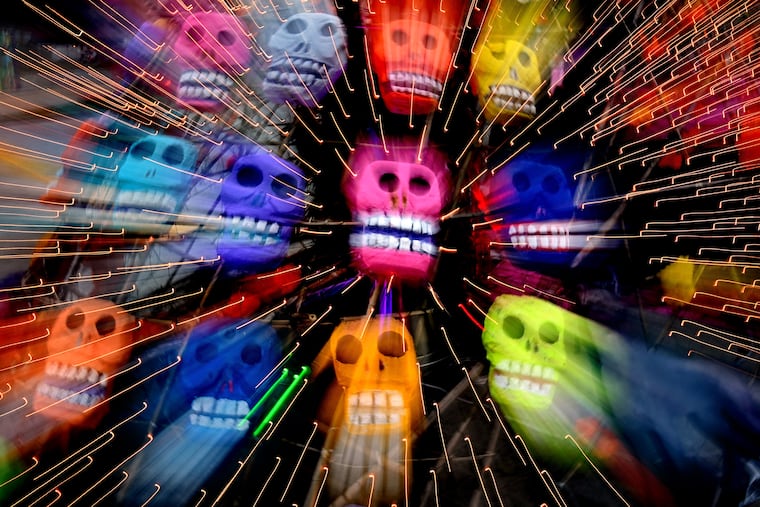 November 8, 2021: The skulls on a Día de los Muertos (Day of the Dead) altar are blurred as the lens is zoomed during the taking of the photo as the Mexican holiday was celebrated in LOVE Park on Nov. 1 and 2. The altar was created by Mexican artist Cesar Viveros, for the day that helps people remember the deceased and honor their memory by building altars. They leave ofrendas (offerings) to their loved ones' souls, including food and drink, orange and yellow flowers, and photos and mementos.