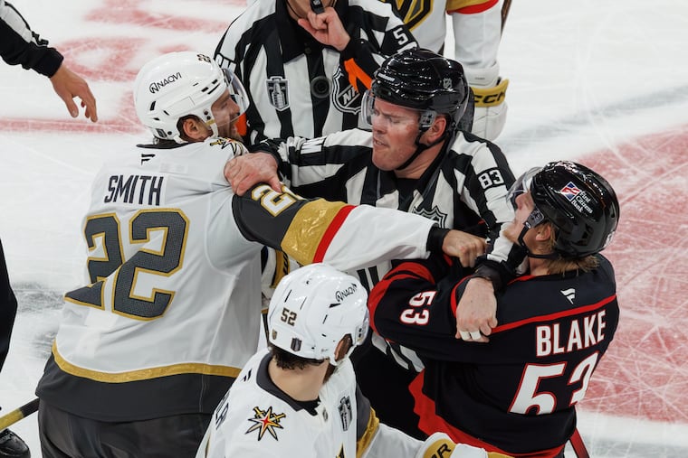 Vegas Golden Knights' Cole Smith (22) and Carolina Hurricanes' Jackson Blake (53) scuffle as an official tries to separate them during Thursday's Game 5 in Raleigh, N.C.
