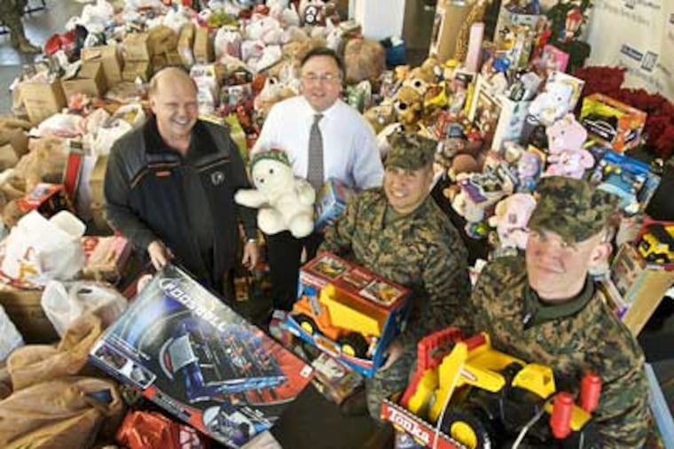 Flyers great Bob Kelly, Philadelphia Media Holdings CEO Brian Tierney, and U.S. Marines Gunnery Sgt. Daniel Gonzalez and Lance Corporal Adam Huff stand among toys donated for the 'Toys for Tots' program. (John Costello / Staff Photographer)