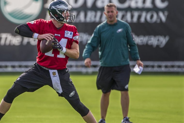 Eagles quarterback Carson Wentz, #11, left, works through the footwork drill of dropping back under the watchful eye of quarterbacks coach, John DeFilippo, right, on Monday morng, the first day fo Eagles tgraining camp. The Eagles begin the first day of training camp at the NovaCare Center on Monday July 24, 2017.