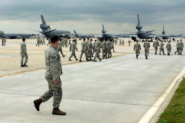 Members of the 514th Air Mobility Wing support crew at the Joint Base head to work Thursday on KC-10 Extenders. The planes are used for aerially refueling U.S. warplanes as they strike ISIS in Iraq and Syria. (Tom Gralish / Staff Photographer)