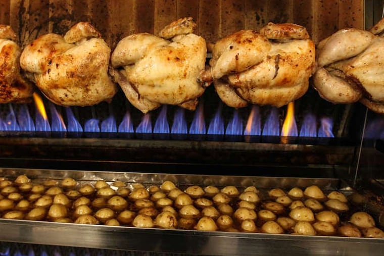 Chickens roasting on a spit, over a pan of potatoes, with the fire in the background, at Petit-Rôti. (STEVEN M. FALK / Staff Photographer )