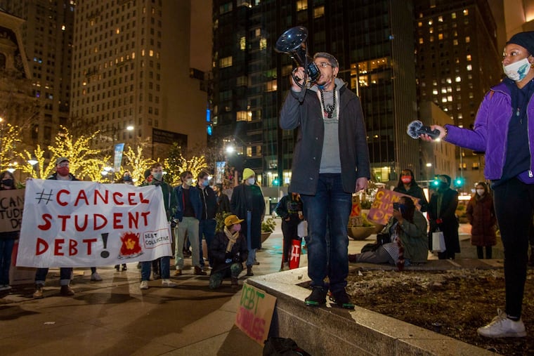 Ismael Jimenez, a social studies and African American studies teacher at Kensington Creative & Performing Arts High School, speaks with a megaphone at a rally outside Biden campaign headquarters at 15th and Market Streets calling for student debt cancellation.