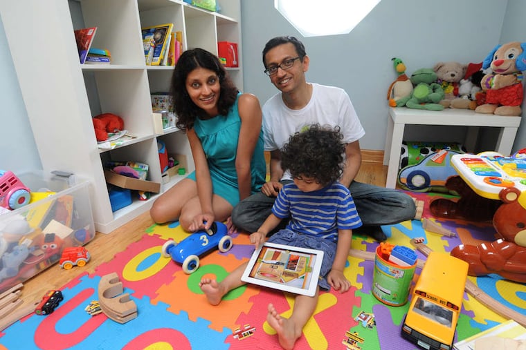 Kartik Hosanagar and his wife, Prasanna Krishnan, watch their son, Aarav Hosanagar, play with their new "ZooPAL - A Gift" on an iPad. They envision it as the first in a series of interactive book/games.