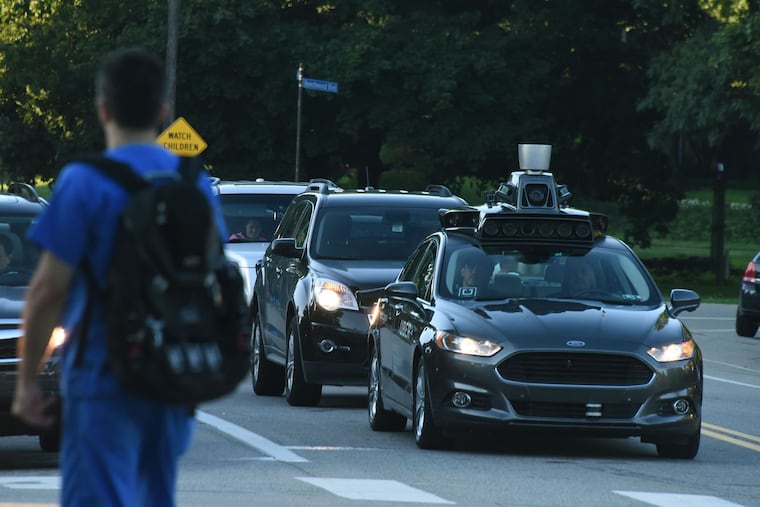 An Uber self-driving Ford Fusion sits at a traffic light on Beechwood Boulevard and waits to turn onto Fifth Avenue in Pittsburgh.