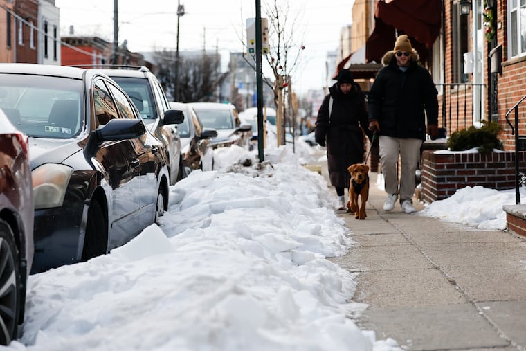 South Philadelphia residents walk their dog along the 1100 block of Mifflin Street with snow covering parts of the sidewalk on Sunday, February 1, 2026.