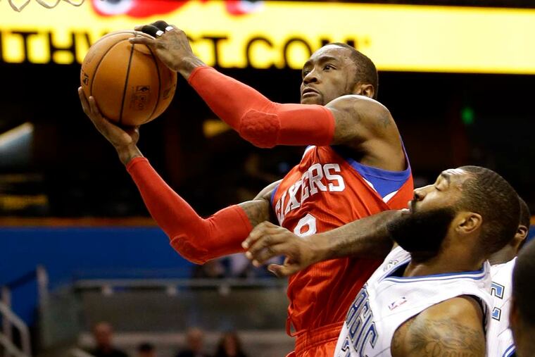 Philadelphia 76ers' Tony Wroten, top, goes to the basket past Orlando Magic's Kyle O'Quinn (2) during the first half. (AP Photo/John Raoux)