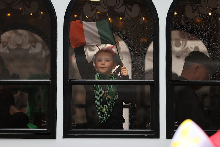 A young participant waves an Irish flag from inside a trolley during the annual Center City St. Patrick's Day Parade in March 2024.