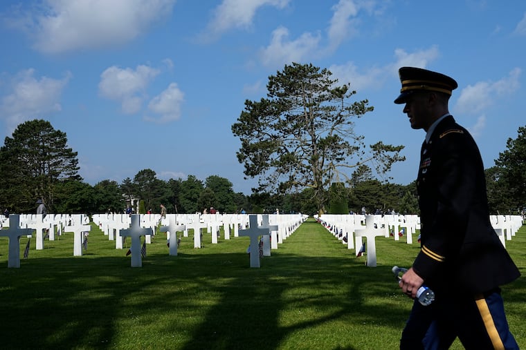 A soldier walks past crosses and flags at a U.S. cemetery near Colleville-sur-Mer, Normandy, in 2024. Vincent Simonetti is in France this week to mark the dedication of a monument to the 8th Army Air Force — of which his grandfather was part — during the 81st celebration of the D-Day landings that helped lead to Hitler's defeat in World War II.