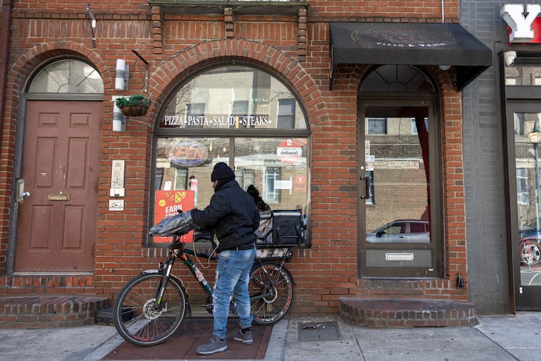 Alhassane Sow, a DoorDash delivery worker, is heading out for a delivery outside of Pat’s Pizza & Pasta in Philadelphia.