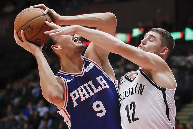 Sixers forward Dario Saric (9) tries to fend off Nets defender Joe Harris during the second quarter Wednesday night.
