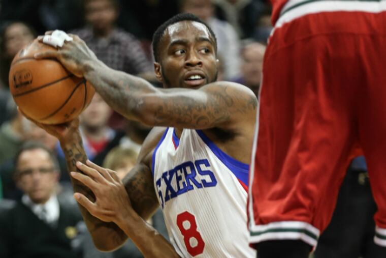 Tony Wroten looks to pass from his knees over Bucks' Jared Dudley. (Steven M. Falk/Staff Photographer)
