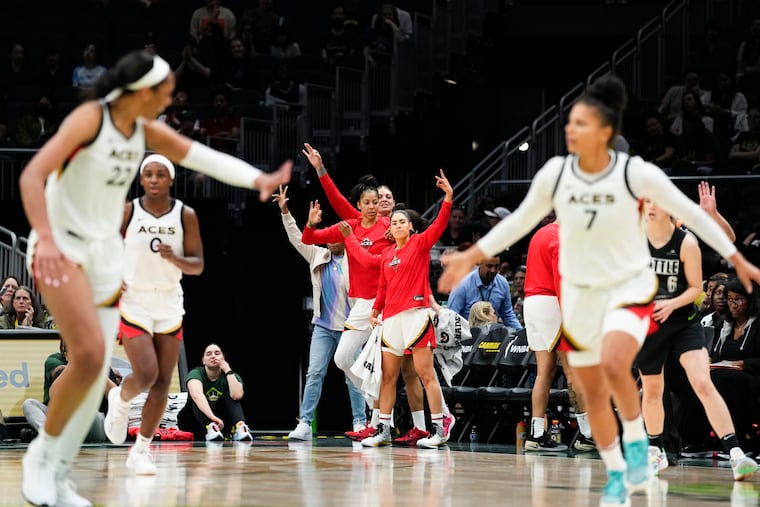 The Las Vegas Aces bench, including forward Candace Parker, left, forward Cayla George, center, and guard Kelsey Plum, right, celebrate an Aces basket as forward A'ja Wilson (22) and forward Alysha Clark (7) greet each other on the court during the second half of a WNBA basketball game against the Seattle Storm, Saturday, May 20, 2023, in Seattle. The Aces won 105-64. (AP Photo/Lindsey Wasson)