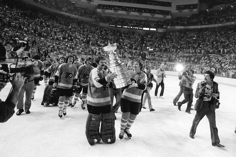 Flyers goalie Bernie Parent and captain Bobby Clarke carry the Stanley Cup in 1975.