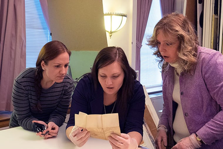 Juliette Honsinger (center), program manager at the National Iron & Steel Heritage Museum in Coatesville, reads one of the soot-covered letters with Le Anne Zolovich (left), communications associate, and Kathy Bratton, collections manager. ED HILLE / Staff Photographer