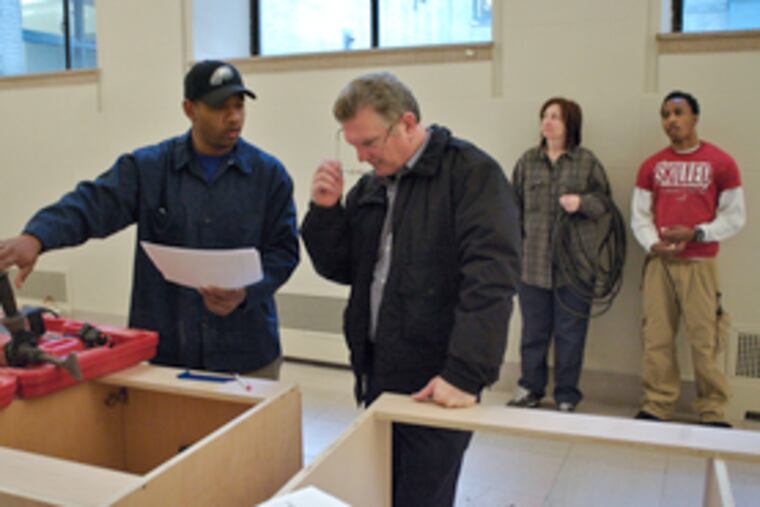 Library electrician Ezekiel Harrell (left) and building superintendent Paul McGeever go over plans before drilling into a wall to prepare the library for a planned cafe.