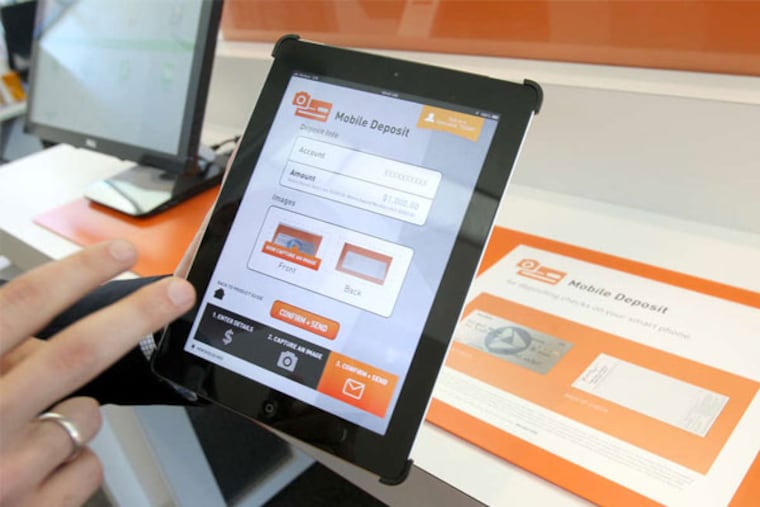 Brendan Penn, a financial consultant at PNC's Malvern branch, makes a deposit using a tablet. (Charles Fox / Staff Photographer)