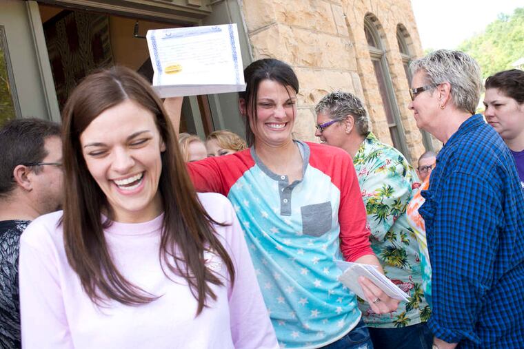 Kristin Seaton holds up her marriage license - the state's first - as she leaves the courthouse in Eureka Springs, Ark., with her partner, Jennifer Rambo.