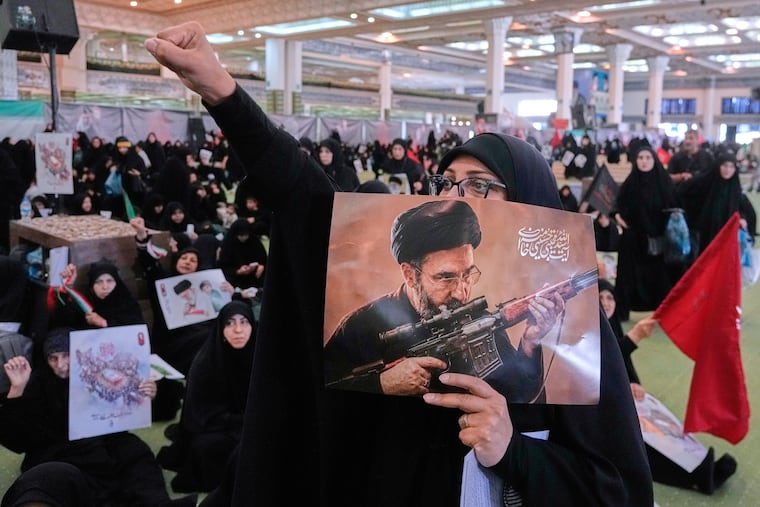 A mourner chants slogan as she holds a poster with graphic depicting Iran's Supreme Leader Ayatollah Mojtaba Khamenei in a ceremony commemorating the late Supreme Leader Ayatollah Ali Khamenei at the Imam Khomeini Mosalla Grand Mosque in Tehran, Tuesday, July 14, 2026.