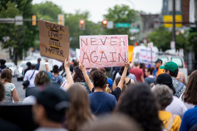 Community members and youth chant and hold signs as they march on 52nd Street for the "March for Our Lives" in West Philadelphia on Saturday.