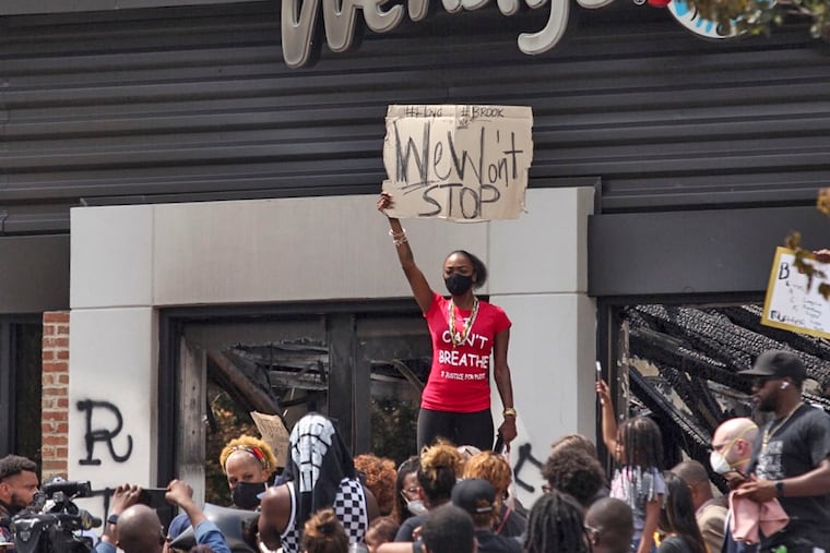 People hold a rally at Wendy's on University Avenue in Atlanta on Sunday. Rayshard Brooks died after a confrontation with police officers at the fast food restaurant in Atlanta on Friday.