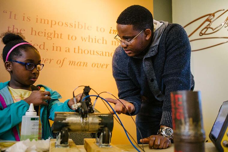 Kirk Butler, B.S., shows Cai Parker, 7, how to use Ultrasonics to test a piece of pipe during the Color of Science program at The Franklin Institute.