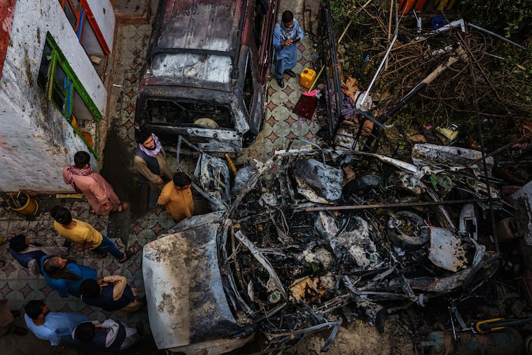 Relatives and neighbors of the Ahmadi family gathered around the incinerated husk of a vehicle that the family says was hit by a U.S. drone strike, killing 10 people, in Kabul, Afghanistan, Aug. 30.