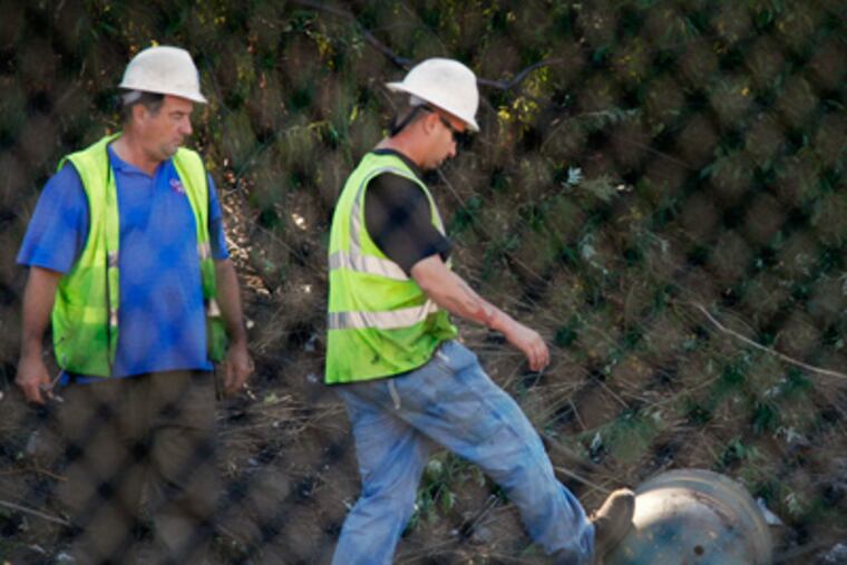 A Conrail worker gives a replica torpedo a kick before walking away from it near a construction site in Port Richmond on Friday. (Alejandro A. Alvarez / Staff Photographer)