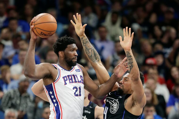 The 76ers' Joel Embiid passes the ball around Orlando's Khem Birch during a game last month. The two squads could meet in the first round of the playoffs.