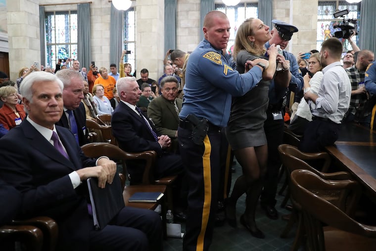 New Jersey State Police remove Sue Altman, state director, New Jersey Working Families, before George E. Norcross III, left, testifies in front of the New Jersey Senate Select Committee on Economic Growth Strategies about his role in the controversial state tax incentive program, on Monday in Trenton, N.J. (David Maialetti/The Philadelphia Inquirer via AP)