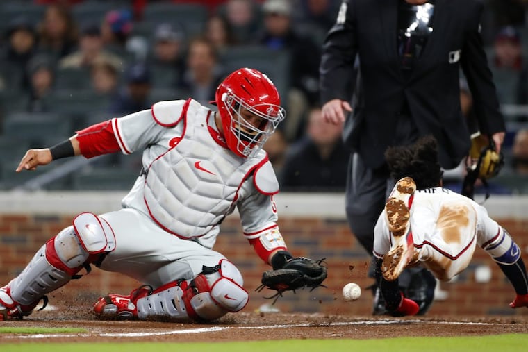 The Braves’ Ozzie Albies scores on a Nick Markakis sacrifice fly as the ball gets away from Phillies catcher Jorge Alfaro in the fourth inning Monday.