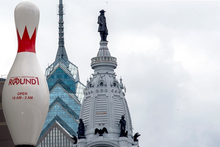 July 26, 2021: A relatively recent addition to the Fashion District and Center City skyline (seen from the Philadelphia Bus Terminal, in the 1000 block of Filbert Street) a large tenpin joins City Hall (right, completed in 1901) and One Liberty Place (center, completed in 1987).