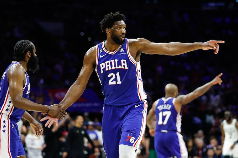 Sixers center Joel Embiid points with teammate guard James Harden.