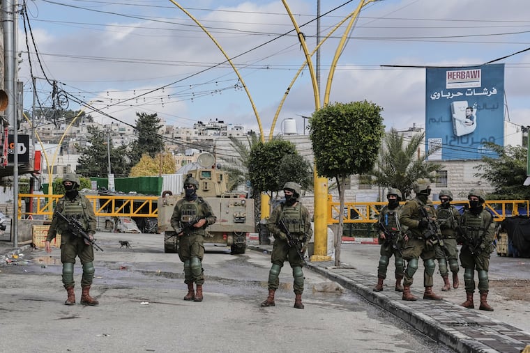 Israeli soldiers take up positions during an army raid in the West Bank city of Hebron Monday, Jan. 19, 2026.