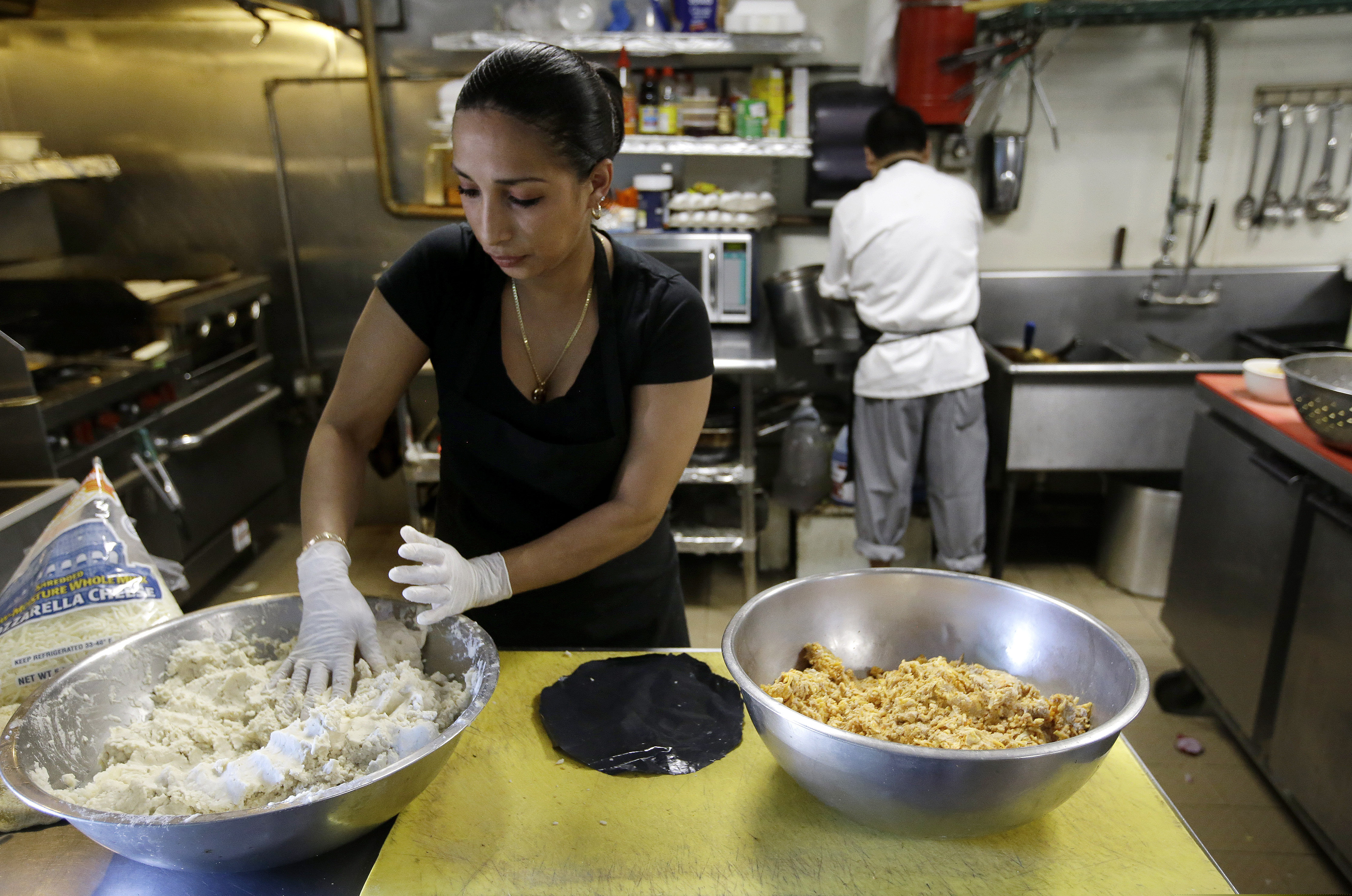 In June, Mariana Moncada, left, originally of Honduras, prepares food in a kitchen, in Chelsea, Mass. The number of Central Americans in the United States has increased over the last decade, and Chelsea has exemplified that trend with a population that is more than 60 percent Latino.