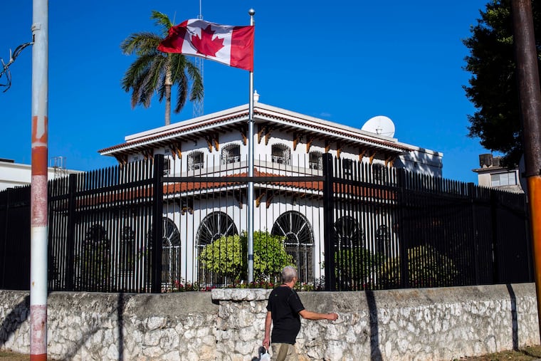FILE - In this April 17, 2018 file photo, a man walks beside Canada's embassy in Havana, Cuba. Canada announced Wednesday, Jan. 30, 2019, it is removing up to half of the Canadians at its embassy in Cuba after another diplomat was found to have fallen mysteriously ill. Canada has confirmed 14 cases of mysterious health problems since early 2017. (AP Photo/Desmond Boylan, File)