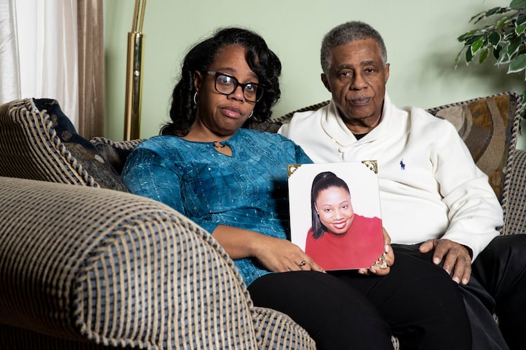 Keisha Cappel, sitting with her father, Alfonso Jones, holds a portrait of her sister, Tamika Jones, who died from COVID-19. EMTs told Jones she didn't need to go to the hospital, a lawsuit filed by the family alleges.