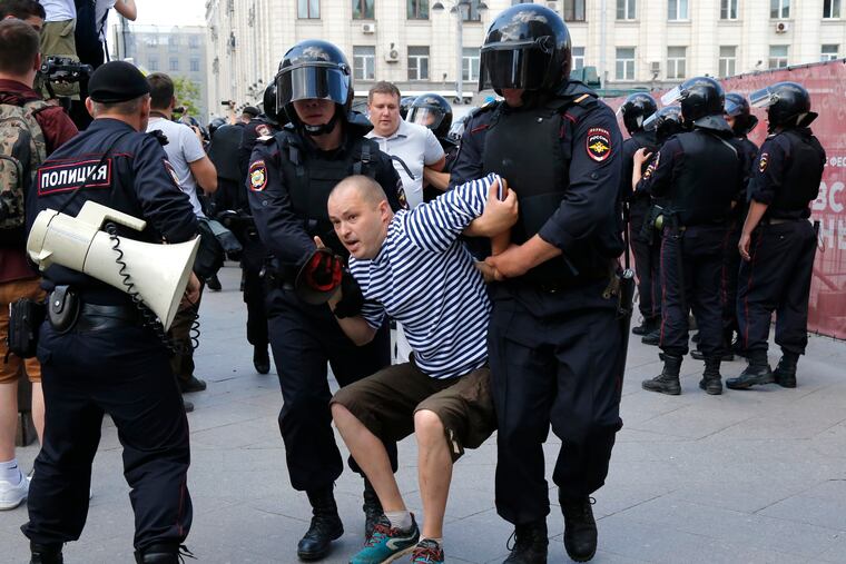Police officers detain a man during an unsanctioned rally in the center of Moscow, Russia, Saturday, July 27, 2019. Russian police on Saturday began arresting people outside the Moscow mayor's office ahead of an election protest demanding that opposition candidates be allowed to run for the Moscow city council.