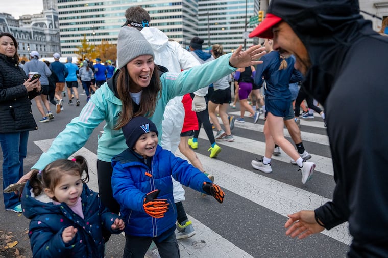 Their children, Quinn, 3, and Cameron, 5, are there as Amanda Carter greets her husband Ron Carter as he makes the turn onto Arch Street at 16th, at the start of the 2024 Philadelphia Marathon Sunday, Nov. 24, 2024. They’re from New York City and this is Ron’s first marathon. Amanda who had done three, says “’m usually the one running.”