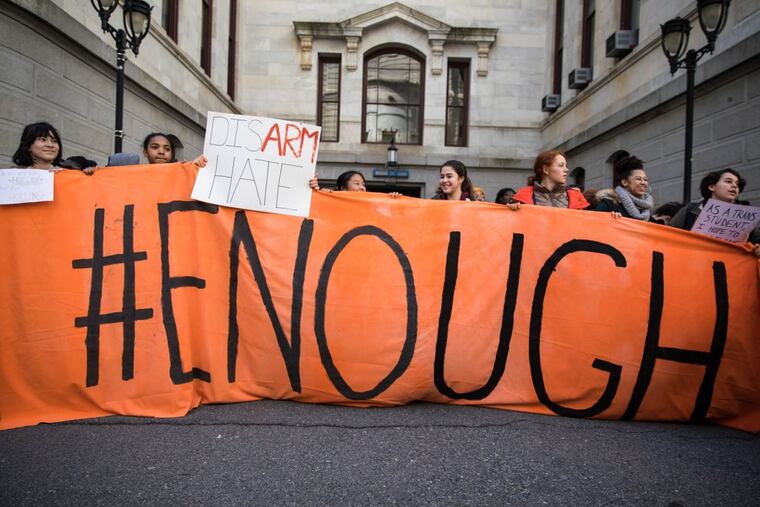 Students from Germantown Friends School hold up a banner that reads "#ENOUGH" during a school walkout held in the City Hall courtyard on Friday, April 20, 2018.