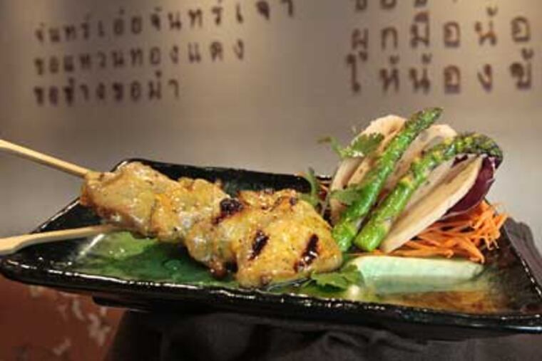Grilled pork skewers at MangoMoon in Manayunk. On the wall are three lines of a lullaby, rendered in 18,600 hammered copper nails. (Elizabeth Robertson / Staff Photographer)