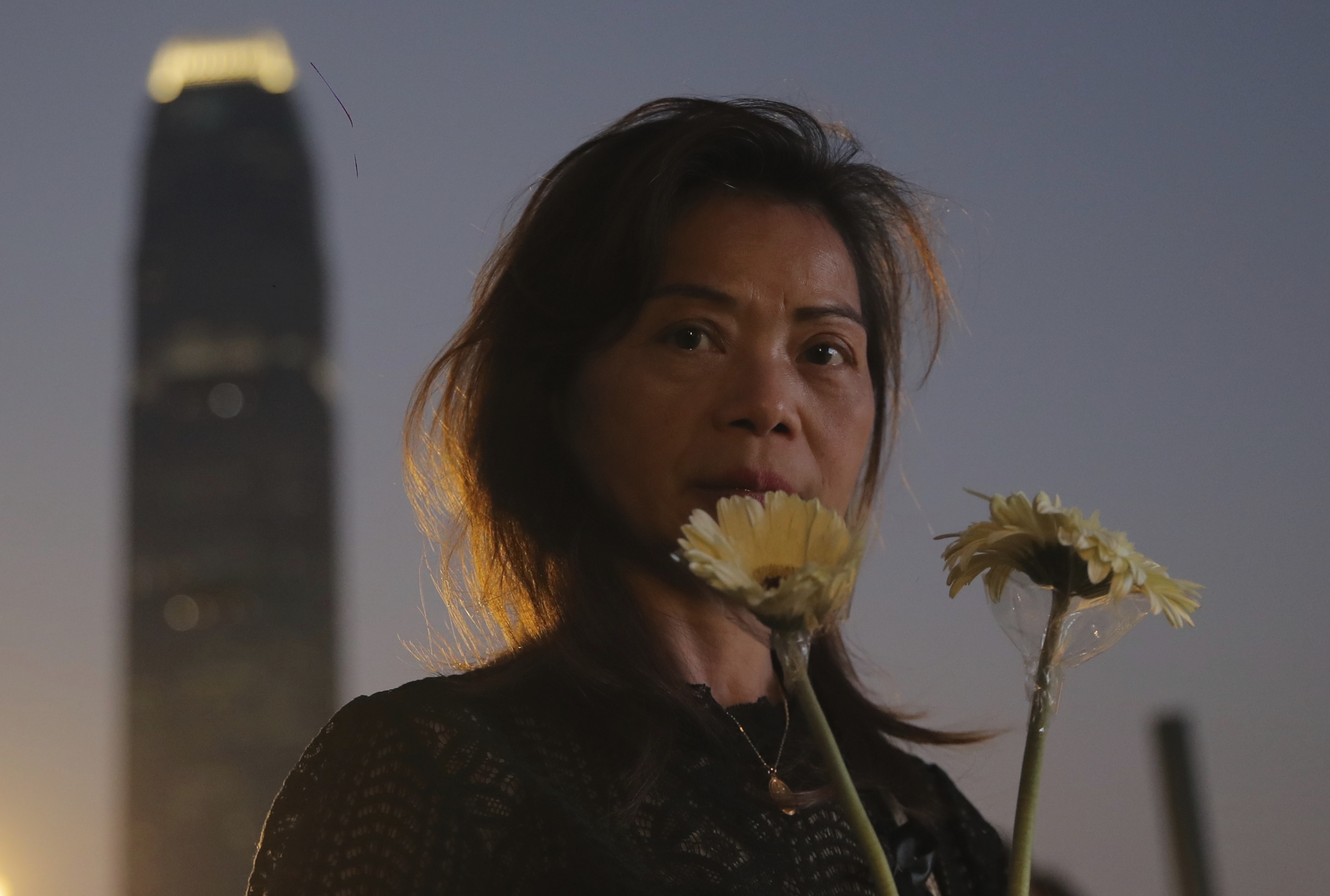 A woman attends a vigil for student Chow Tsz-Lok in Hong Kong, Saturday, Nov. 9, 2019. Chow Tsz-Lok, the Hong Kong university student who fell off a parking garage after police fired tear gas during clashes with anti-government protesters died Friday in a rare fatality in five months of unrest, fueling more outrage against authorities in the semi-autonomous Chinese territory.