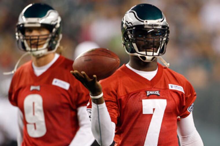 Eagles' quarterback Michael Vick holds the football as Nick Foles stands in the background during Flight Night full-team practice on Sunday, August 26, 2012. ( Yong Kim / Staff Photographer )