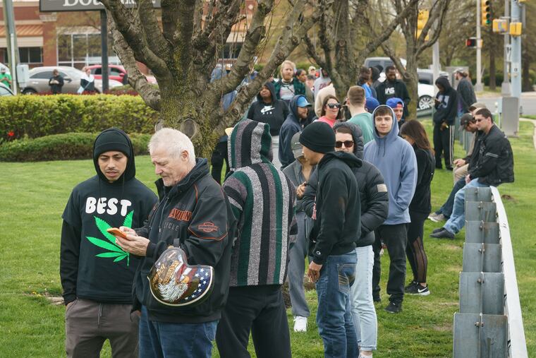 Moises Perez (front left) and Mark Slaymaker (front second from left) talk while waiting in line at The Botanist in Williamstown, on the first day of recreational cannabis sales in New Jersey, Thursday, April 21, 2022.