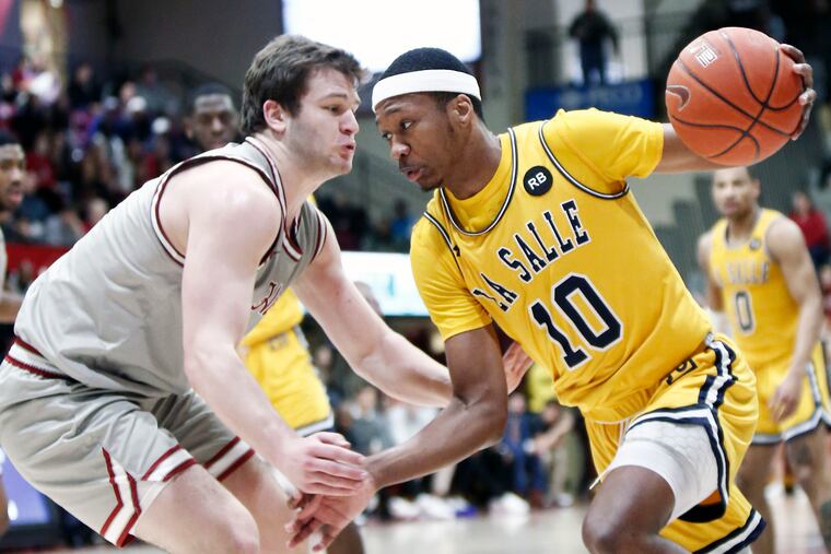 La Salle guard Isiah Deas drives on St. Joe’s guard Ryan Daly in the Explorers' win on Saturday at Hagan Arena.