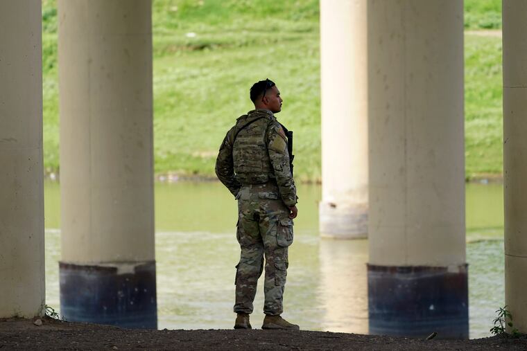 A member of the Texas National Guard looks across the Rio Grande to Mexico from the U.S. side of the border at Eagle Pass, Texas, on Aug. 26.
