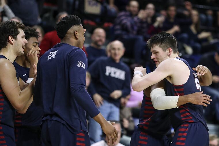 Penn forward A.J. Brodeur (right) hugs his teammates as he checks out of the game against Columbia at the Palestra.