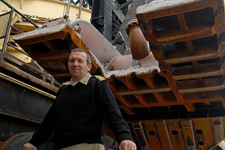 U.S. Army Corps of Engineers Capt. Karl A. Van Florcke poses Monday under the grate on the drag head of the pump on board the dredge McFarland. The 24-pound cannon ball and other historic treasures were found in the grate earlier this month. (Tom Gralish / Staff Photographer)